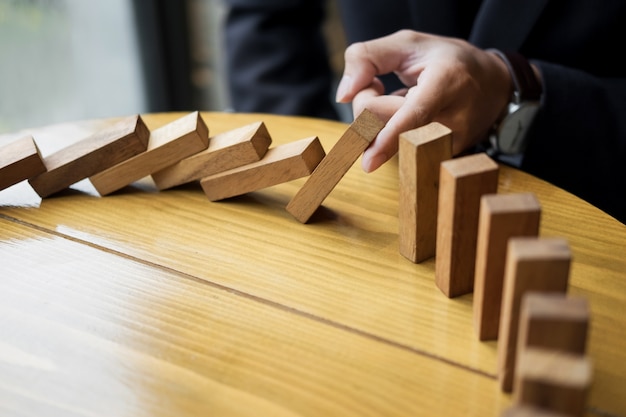 businessman hand stop dominoes continuous toppled or risk with copyspace.