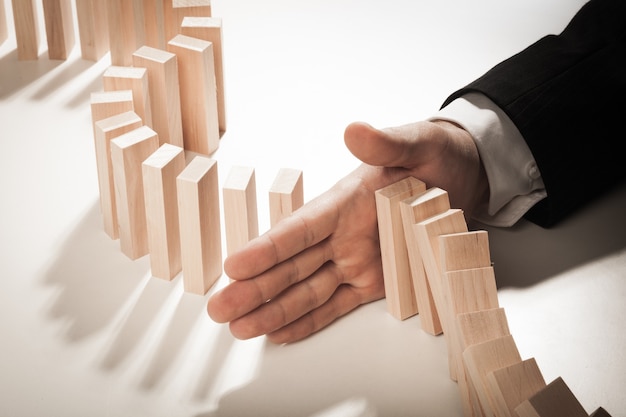 Businessman Hand Stop Falling Domino Pieces