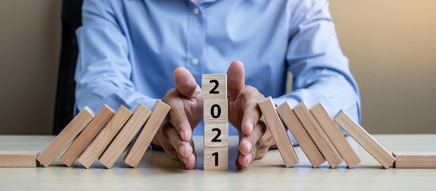 Businessman hand Stopping Falling of wooden Blocks 