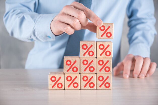 Businessman hand takes a wooden cube block depicting,shown the percentage symbol icon. Interest rate financial and mortgage rates concept.