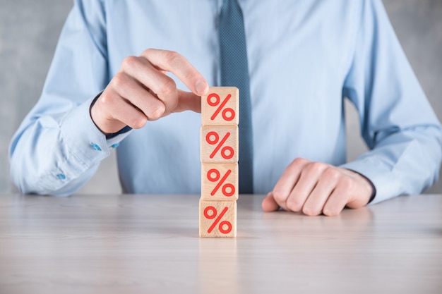 Businessman hand takes a wooden cube block showing the percentage symbol.