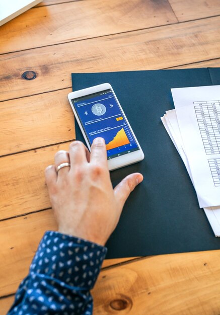 Businessman hand touching mobile screen with bitcoins