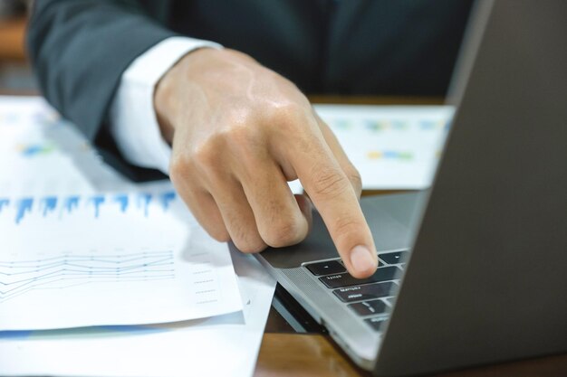 Businessman hand use laptop and analysis the graph at the home office for setting challenging business goals and plan to achieve the new target