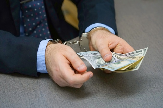 Businessman in handcuffs with a bribe