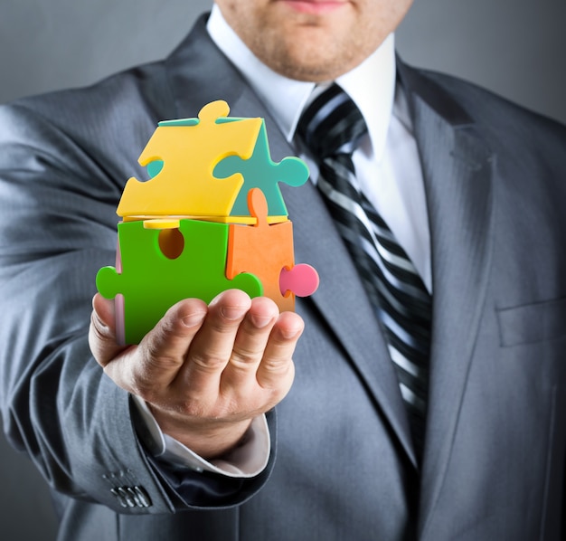 Businessman handling colorful puzzle house