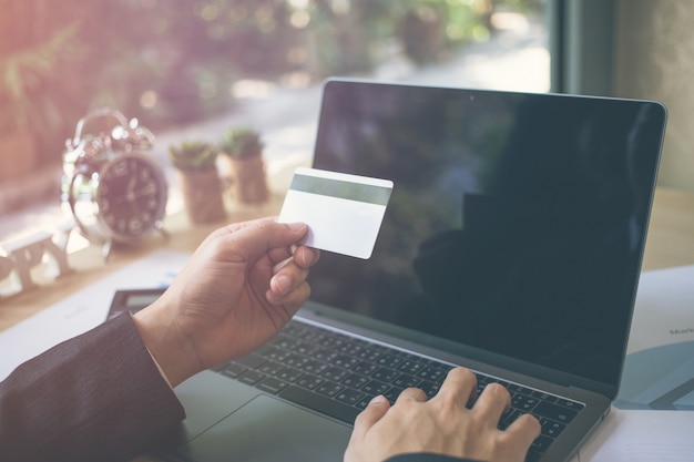 Businessman hands holding credit card typing numbers on computer keyboard