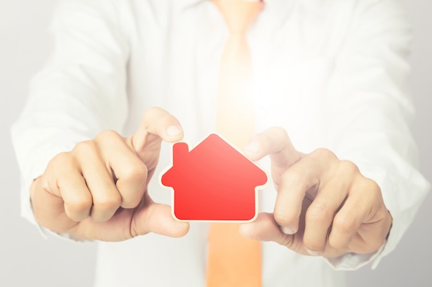 Businessman hands  holding the wooden cut house shape, isolated background