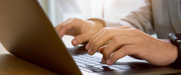 Businessman hands using laptop computer with the press keyboard at office. proportion of the banner for ads.