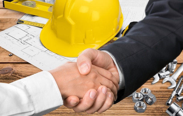 Businessman handshake with the architect on background