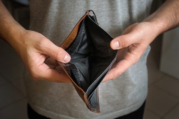 Businessman has no money, unemployed and bankrupt man looks into his empty wallet.