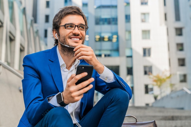 屋外のビジネスセンターの近くに座って電話をしているビジネスマン