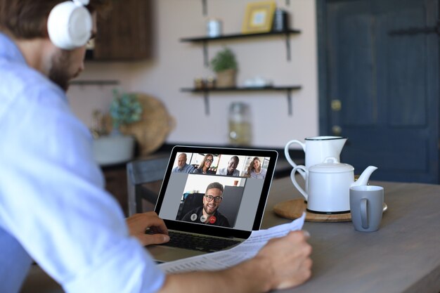 Businessman in headphones speak talk on video call with colleagues on online briefing