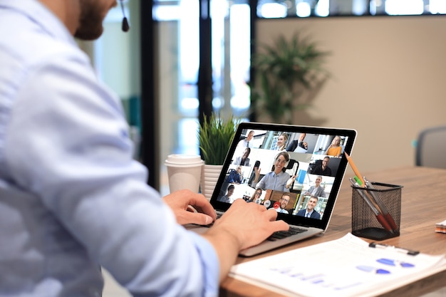 Businessman in headphones talking to her colleagues in video conference