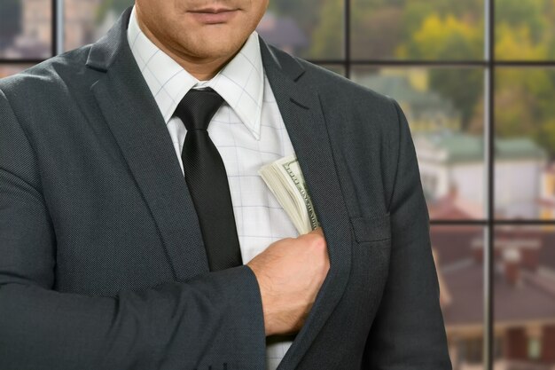 Businessman hiding dollars into jacket.