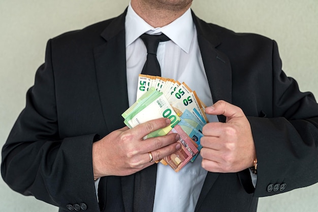 Businessman hiding euro bills in a suit pocket Concept of corruption or illegal businesses