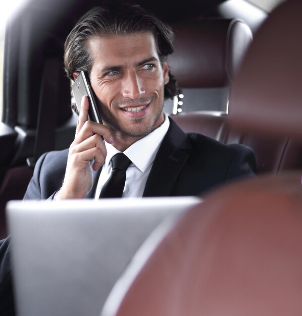 Businessman in his car with a laptop talking on the phone