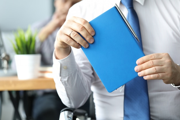 Businessman hold blue diary in hand.