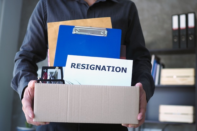 Businessman hold boxes for personal belongings and resignation letters