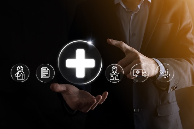 Businessman hold virtual plus medical network connection icons. Covid-19 pandemic develop people awareness and spread attention on their healthcare.Doctor,document,medicine,ambulance,patient icon.