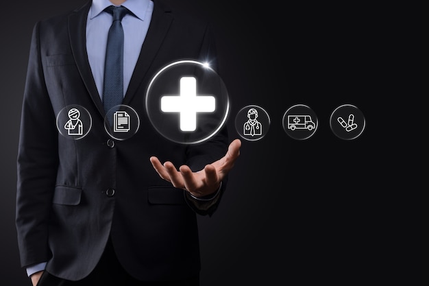 Businessman hold virtual plus medical network connection icons. Covid-19 pandemic develop people awareness and spread attention on their healthcare.Doctor,document,medicine,ambulance,patient icon.