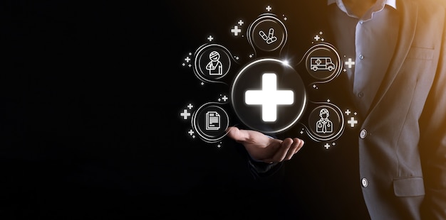 Businessman hold virtual plus medical network connection icons. Covid-19 pandemic develop people awareness and spread attention on their healthcare.Doctor,document,medicine,ambulance,patient icon.