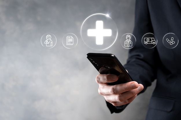 Businessman hold virtual plus medical network connection icons. Covid-19 pandemic develop people awareness and spread attention on their healthcare.Doctor,document,medicine,ambulance,patient icon.