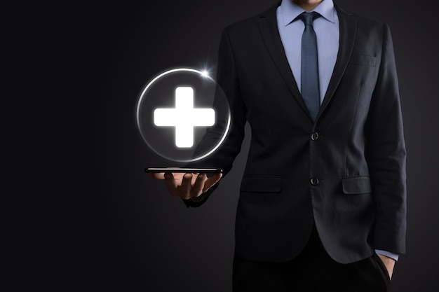 Businessman hold virtual plus medical network connection icons. Covid-19 pandemic develop people awareness and spread attention on their healthcare.