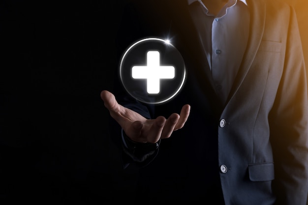 Businessman hold virtual plus medical network connection icons. Covid-19 pandemic develop people awareness and spread attention on their healthcare.