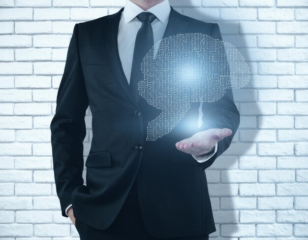 Photo businessman holding abstract digital human brain hologram on white brick background with shadow computer technologies concept