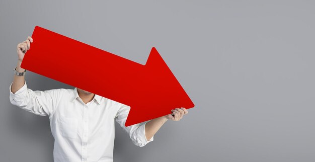 Photo businessman holding big red graph chart arrow that is pointing down at blurry of grey background concept of global recession