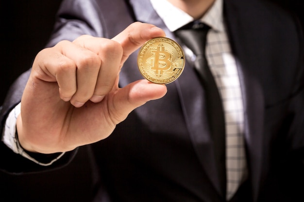 Businessman holding bitcoin on black background