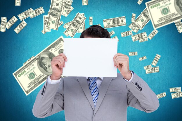 Businessman holding blank sign in front of his head against blue background