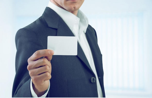 Businessman holding blank visit card on background