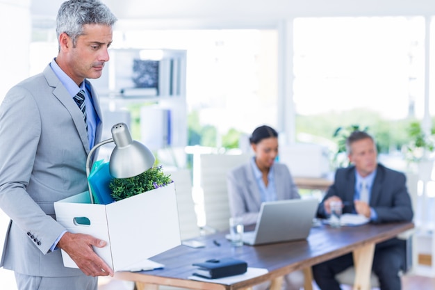 Businessman holding box with his colleagues behind him 