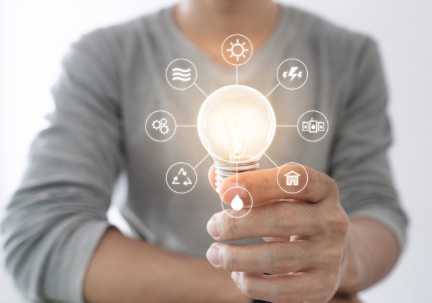 Photo businessman holding bright light bulb with energy resources icon