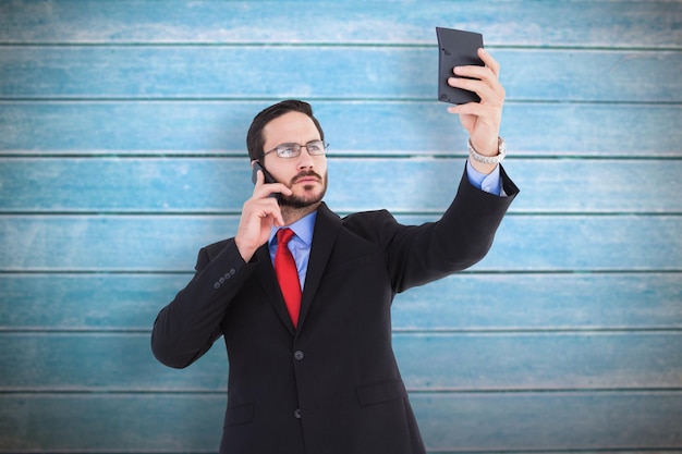 Бизнесмен держит калькулятор во время разговора по телефону против деревянных досок