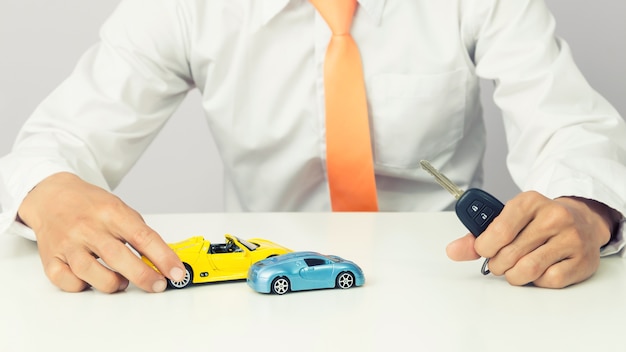 Businessman holding a car keys and miniature car model, Auto business and financial concept