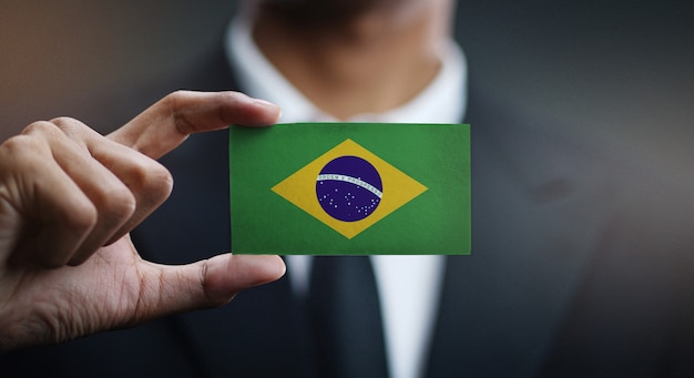 Photo businessman holding card of brazil flag