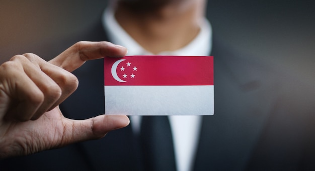 Uomo d'affari holding card della bandiera di singapore