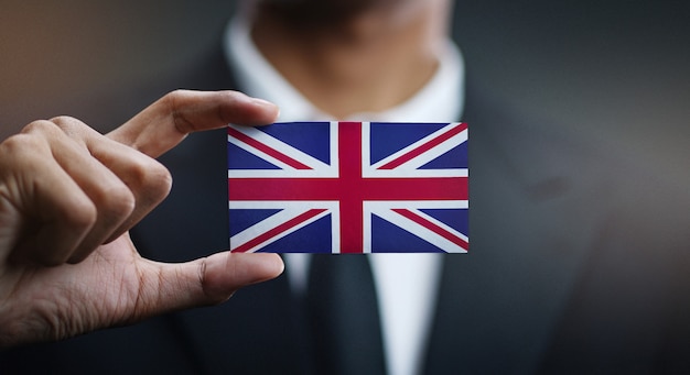 Бизнесмен, держа карты Великобритании флаг
