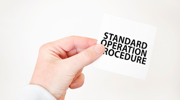 Businessman holding a card with text STANDARD OPERATION PROCEDURE business concept