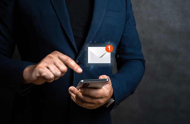 Photo businessman holding cellphone with virtual letter icon for application notification alert concept hand of businessman using smartphone for email with notification alert online communication concept