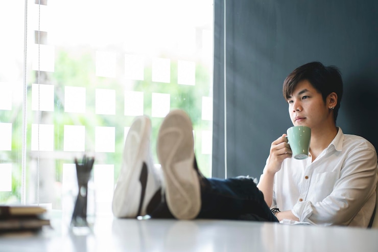 Photo 持咖啡杯的商人坐在办公室里