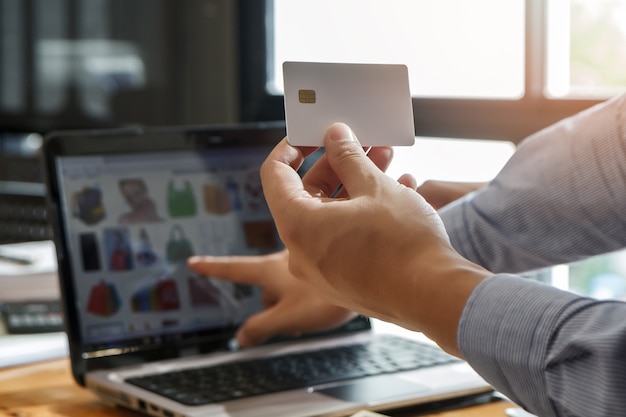 Businessman holding credit card and using laptop.