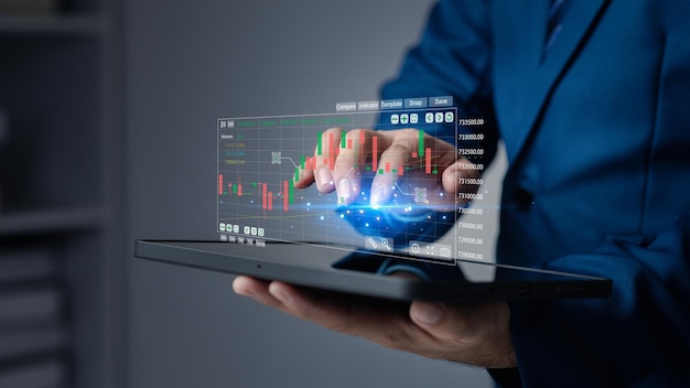 Businessman holding a device with a stock chart hologram investing using technology to invest in stocks The concept of using technology in trading and analyzing stocks