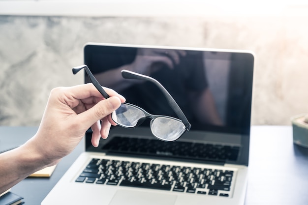 Businessman holding eyeglasses and working on the desk