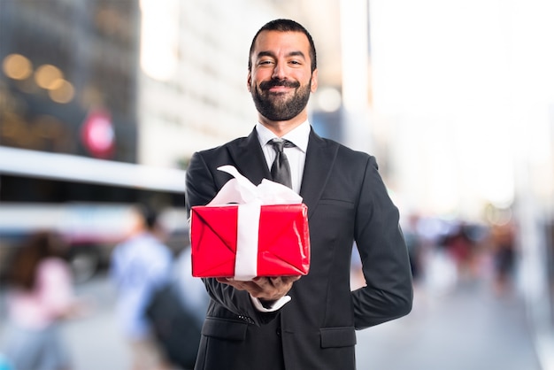 Businessman holding a gift on unfocused background