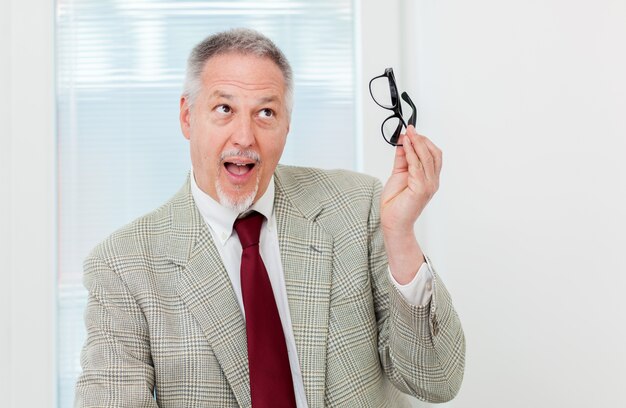 Businessman holding glassesand having an idea