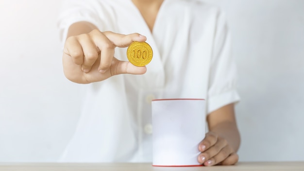 Businessman holding gold coins putting in coin bank. concept saving money for finance accounting
