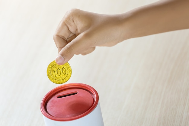 Businessman holding gold coins putting in coin bank